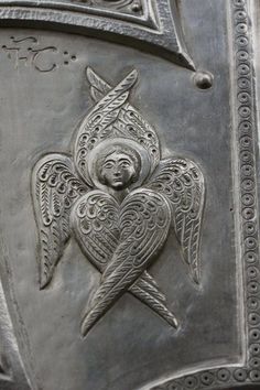 an intricately designed metal door with angel and heart carvings on it's sides