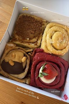 a box filled with different types of pastries on top of a wooden table next to a strawberries