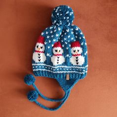 a knitted hat with three polar bears on it and a blue pom - pom