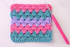 a crochet granny with a pink handled knitting needle