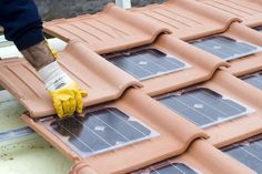 a man in yellow gloves is installing solar panels on the roof