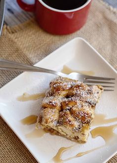 a square white plate topped with dessert next to a cup of coffee and a fork