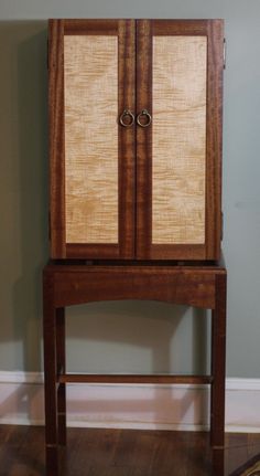 a wooden cabinet sitting on top of a hard wood floor next to a white wall