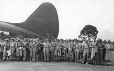 a group of people standing next to each other in front of an old air plane