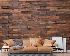 a brown leather couch sitting in front of a wall covered in wood planks and pillows