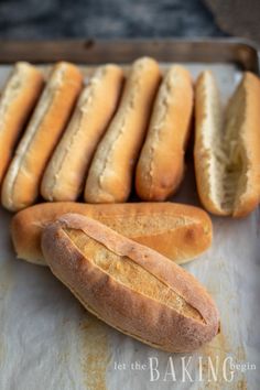 several long loaves of bread sit on a baking sheet next to each other,