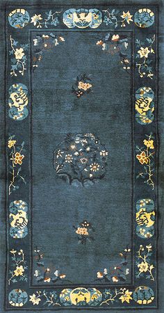 a blue area rug with flowers and vines on the border, in front of a black background