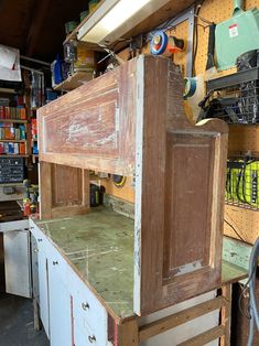 an old wooden cabinet is being worked on in a garage with tools and other items