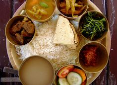 a plate with rice, meats and vegetables on it next to some soup in small bowls