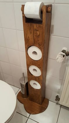 a wooden stand with four rolls of toilet paper on it next to a white toilet