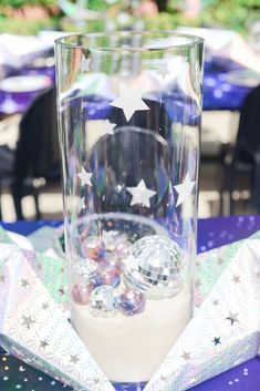 a clear glass with silver stars on it sitting on top of a purple table cloth