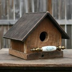 a wooden birdhouse with a pipe sticking out of it's roof and on top of a table