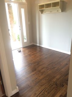 an empty room with hard wood flooring and open closet doors on either side of the door