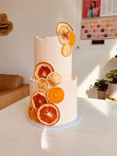 a three tiered cake with orange slices on the top and bottom, sitting on a table