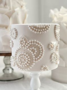 a white cake decorated with pearls and beads