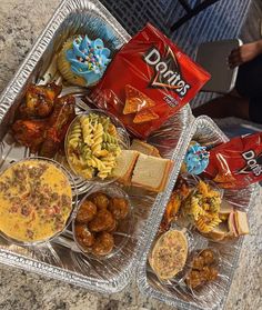 two trays filled with food on top of a table next to a bag of chips