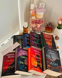 a pile of books sitting on top of a white table next to a vase filled with flowers