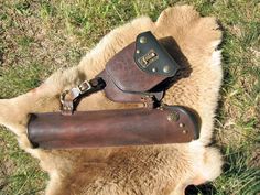 two leather gadgets laying on top of a fur rug in the middle of grass