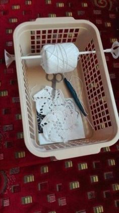 yarn and scissors in a basket on a red tableclothed area with white crochet