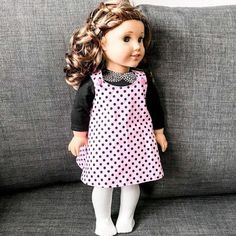 a doll is sitting on a couch wearing a pink and black polka dot dress