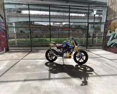 a motorcycle parked in front of a fence with graffiti on the walls and flooring