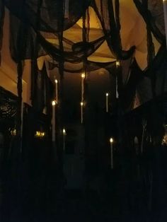 some candles are lit in the dark with sheer curtains hanging from it's ceiling