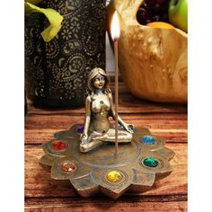 a candle holder with a woman sitting on top of it and seven chakras