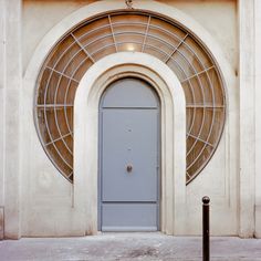 a blue door is in front of a white building with an arched window on the side