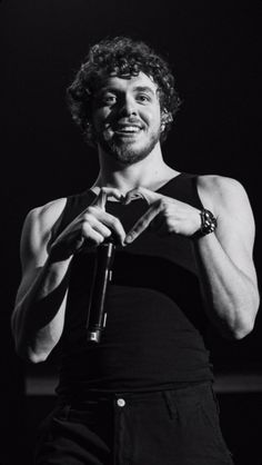 a man holding a microphone in his right hand and making a heart shape with his left hand