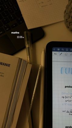 a tablet computer sitting on top of a desk next to a pen and notebooks