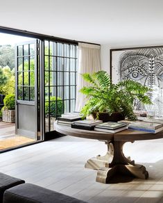 a table with books and plants on it in front of a sliding glass door that leads to a patio