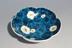 a blue and white bowl with flowers on the inside is sitting on a gray surface