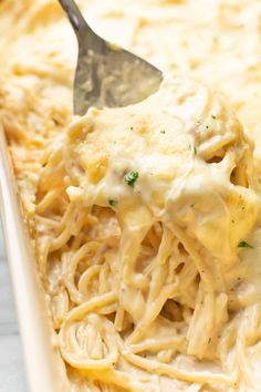 a spoon full of chicken alfredo in a casserole dish