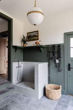 a bathroom with green and white walls, gray tile flooring and a hanging light fixture