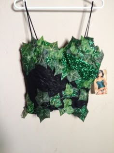 a green and black piece of clothing hanging on a white wall next to a hanger