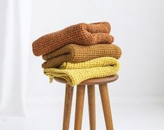 a stack of folded towels sitting on top of a wooden stool