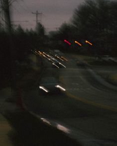 blurry image of cars driving down the road at night with street lights in the background