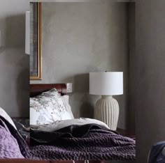 a bedroom with a bed, mirror and lamp on the wall next to each other