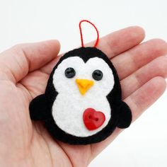 a hand holding a small felt penguin ornament