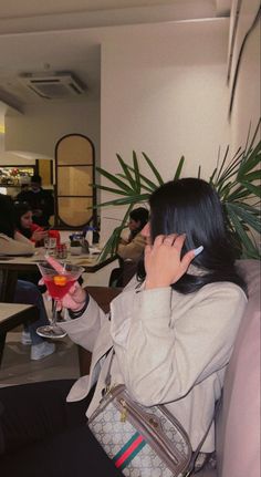 a woman talking on her cell phone while holding a drink