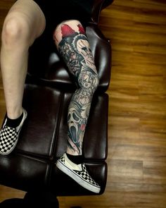 a person sitting in a chair with tattoos on their legs