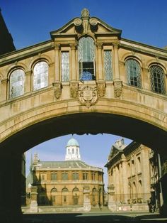 an arched bridge over a street with buildings in the background