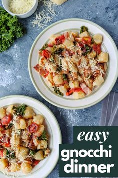 two white plates filled with pasta and spinach on top of a blue tablecloth