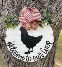 a welcome to our farm sign hanging on a tree with a red and white bow