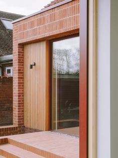 an open door to a brick building with steps leading up to the front entrance and patio area