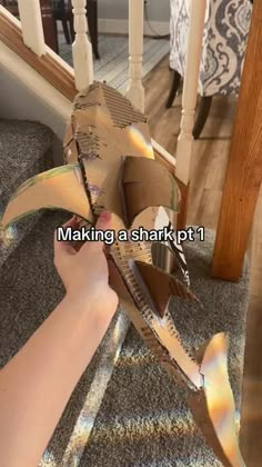 someone is making a shark out of an open shoe box on the carpeted floor