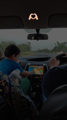 two people are sitting in the back seat of a car and one person is using a tablet