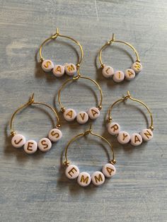 four small personalized hoop earrings on a wooden surface with the word mama spelled in white letters