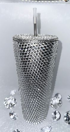 a silver vase with lots of diamonds around it on a white surface and some lights in the background