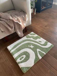 a green and white rug sitting on top of a wooden floor next to a chair